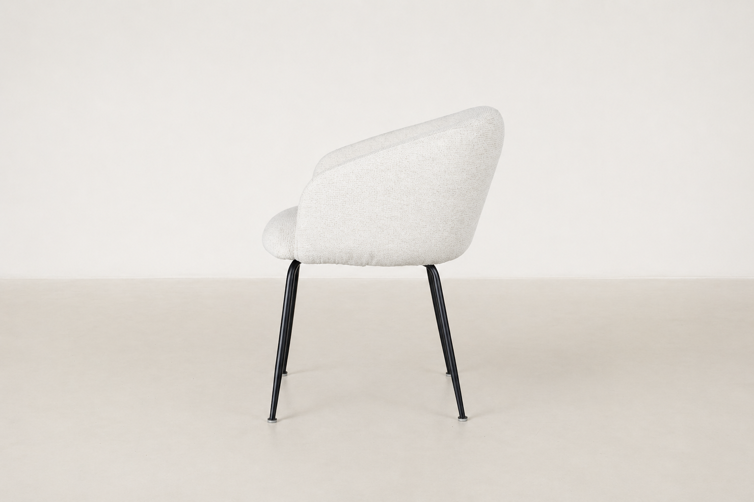 Chic boucle dining chair with curved backrest and black steel legs, styled for a modern dining space.