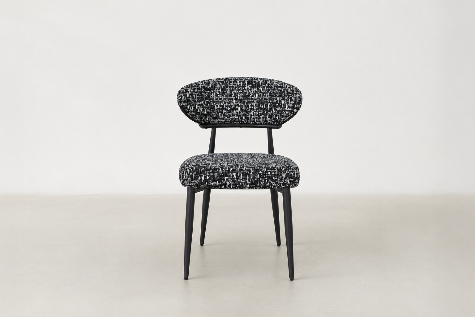"Savvy black and white tweed upholstered dining chair with black powder-coated legs and curved backrest.
"