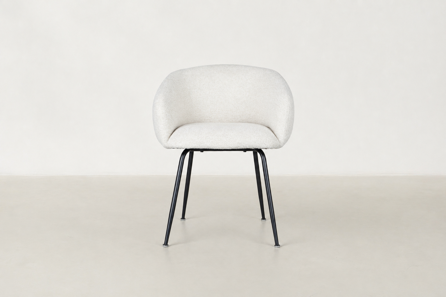 Chic boucle dining chair with curved backrest and black steel legs, styled for a modern dining space.