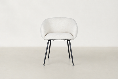 Chic boucle dining chair with curved backrest and black steel legs, styled for a modern dining space.