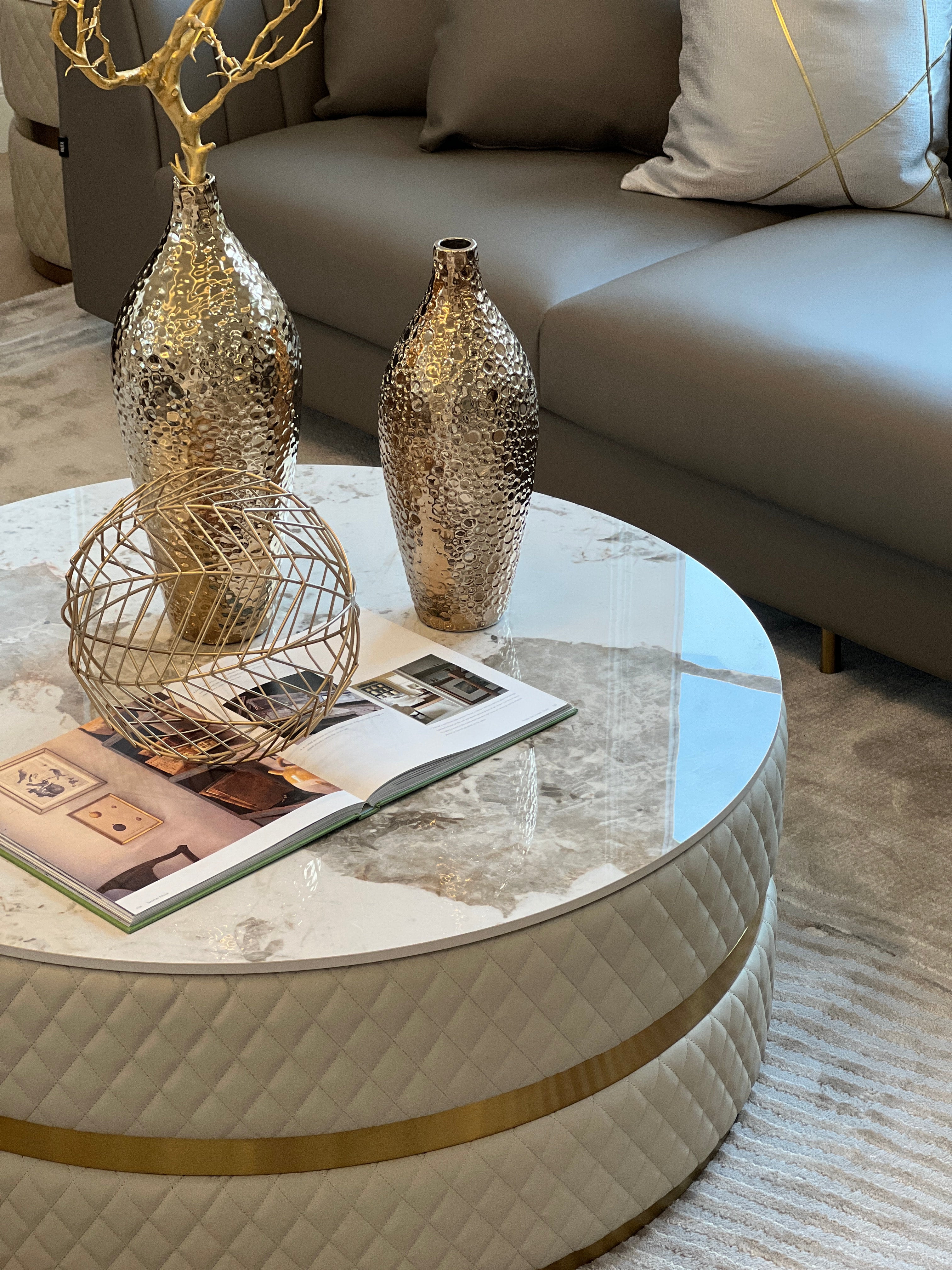 Sassaste luxury round coffee table with faux-marble top, quilted PU leather base, and gold accent banding.