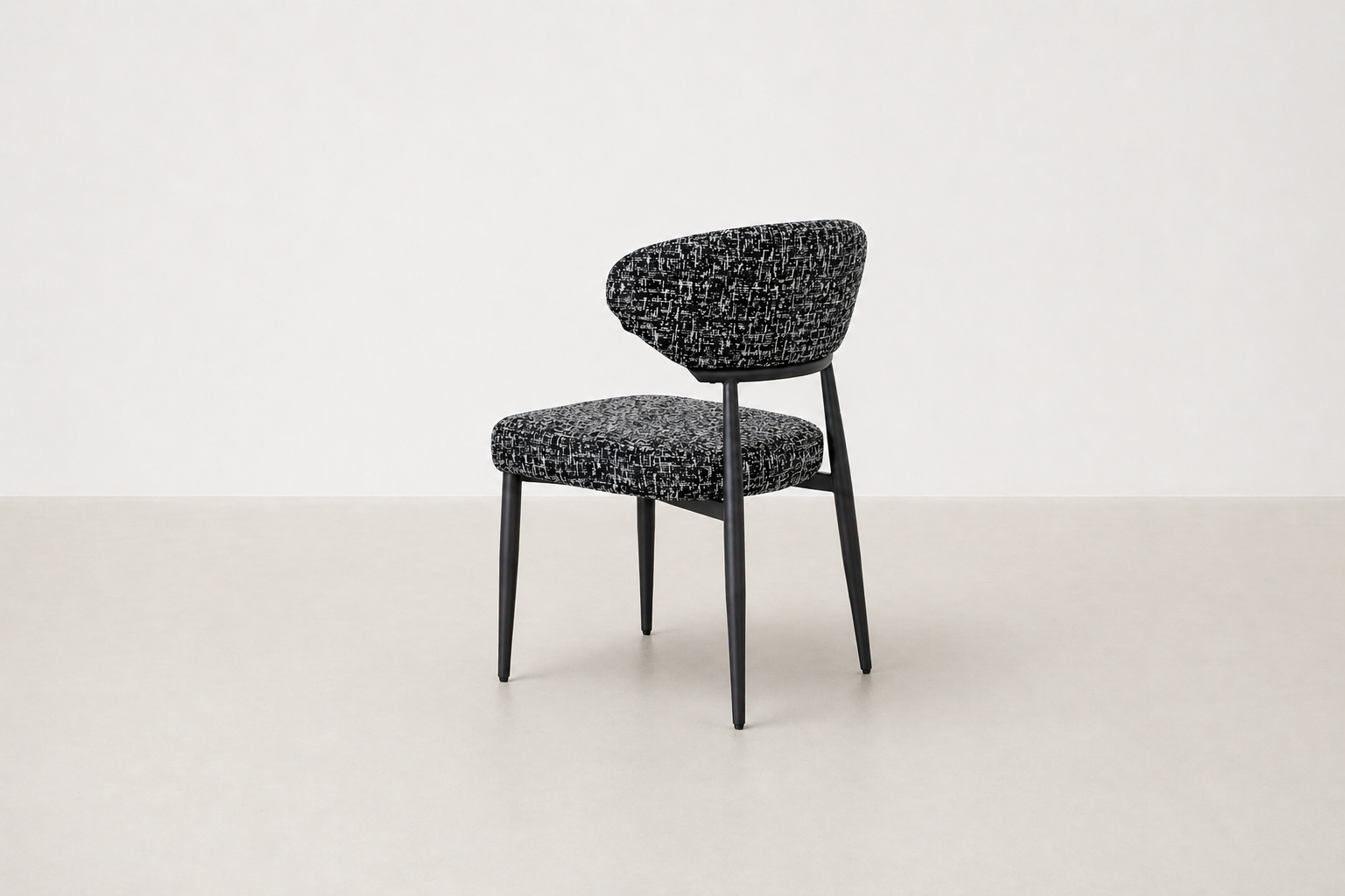 "Savvy black and white tweed upholstered dining chair with black powder-coated legs and curved backrest.
"