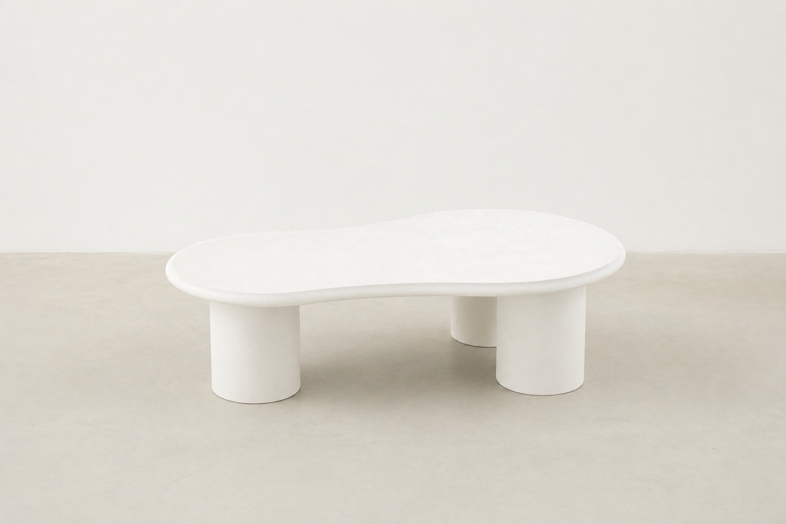 Sculpt kidney shaped coffee table in white concrete with matte finish and cylindrical legs, Japandi modern style.