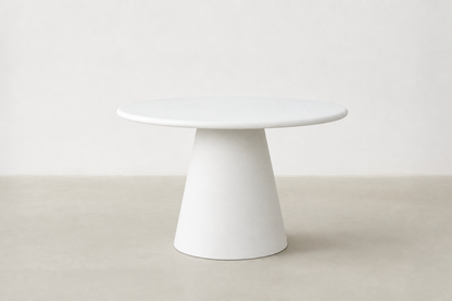 Stratum round pedestal dining table with white-cream concrete finish and sculptural cone base in Japandi style.