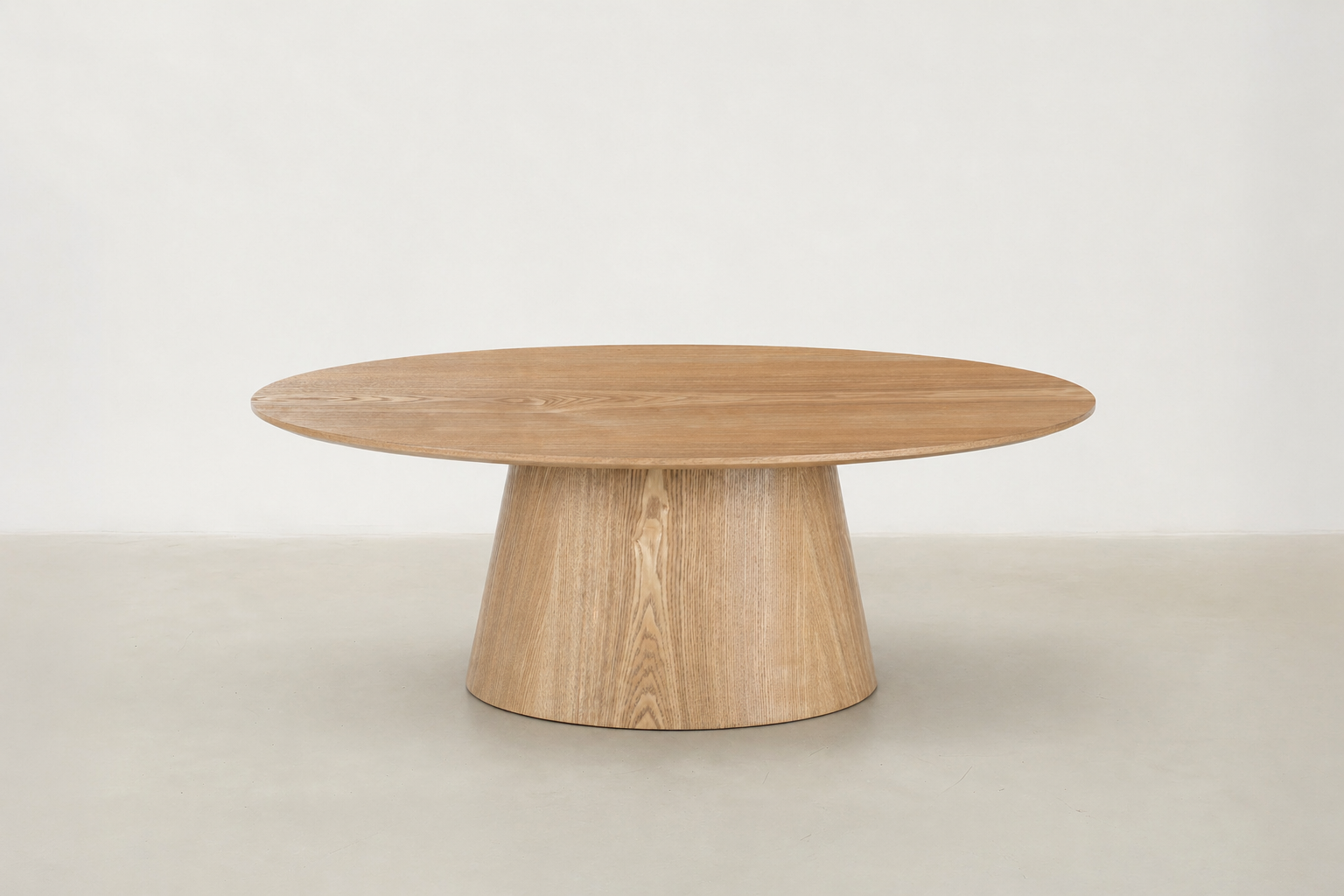 Side view of Zen Coffee Table showing its curved oak pedestal base and low-profile silhouette